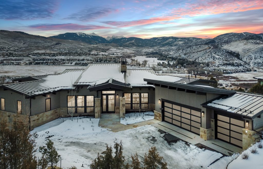 Modern custom home in Eagle County, Colorado built by H&C Construction, featuring mountain views, metal roofing, and a three-car garage in a winter setting