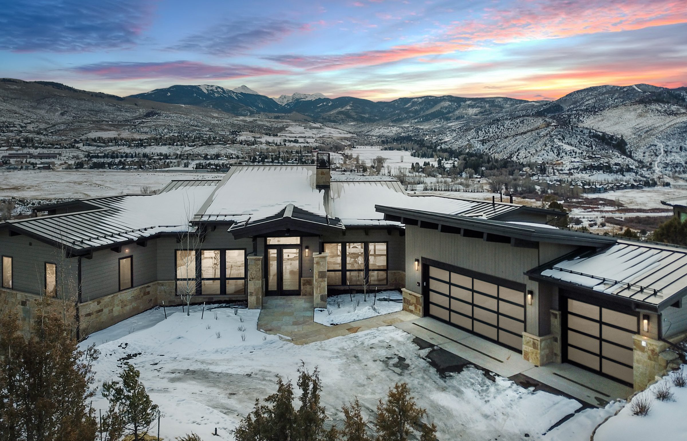 Modern custom home in Eagle County, Colorado built by H&C Construction, featuring mountain views, metal roofing, and a three-car garage in a winter setting