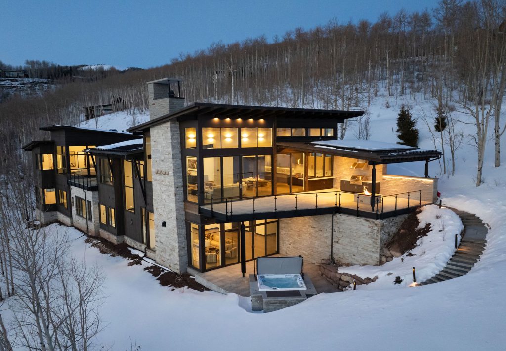 Luxury mountain home in Vail Valley built by H&C Construction, featuring floor-to-ceiling windows, modern stonework, and a snow-covered landscape