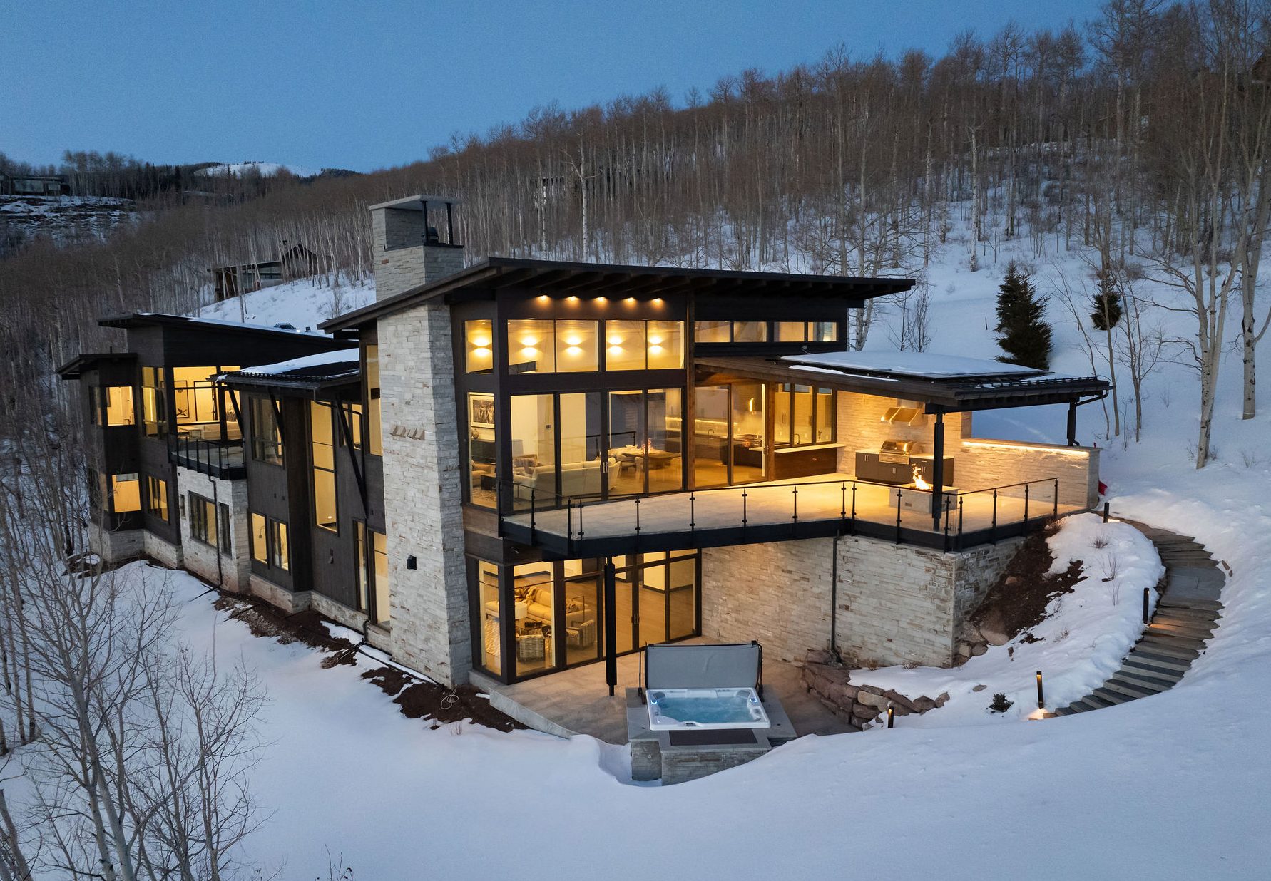 Luxury mountain home in Vail Valley built by H&C Construction, featuring floor-to-ceiling windows, modern stonework, and a snow-covered landscape