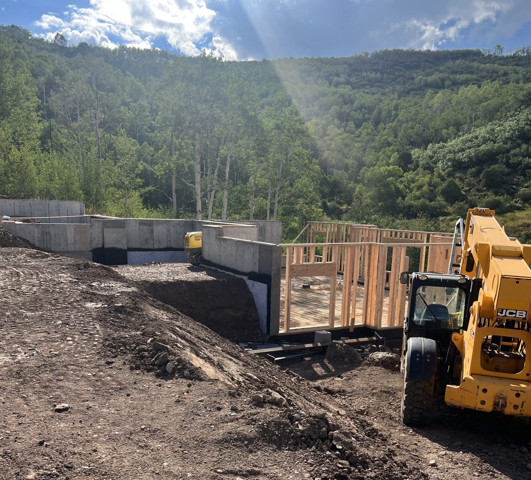 Early stages of luxury home construction with concrete foundation walls and heavy equipment in Avon, Colorado