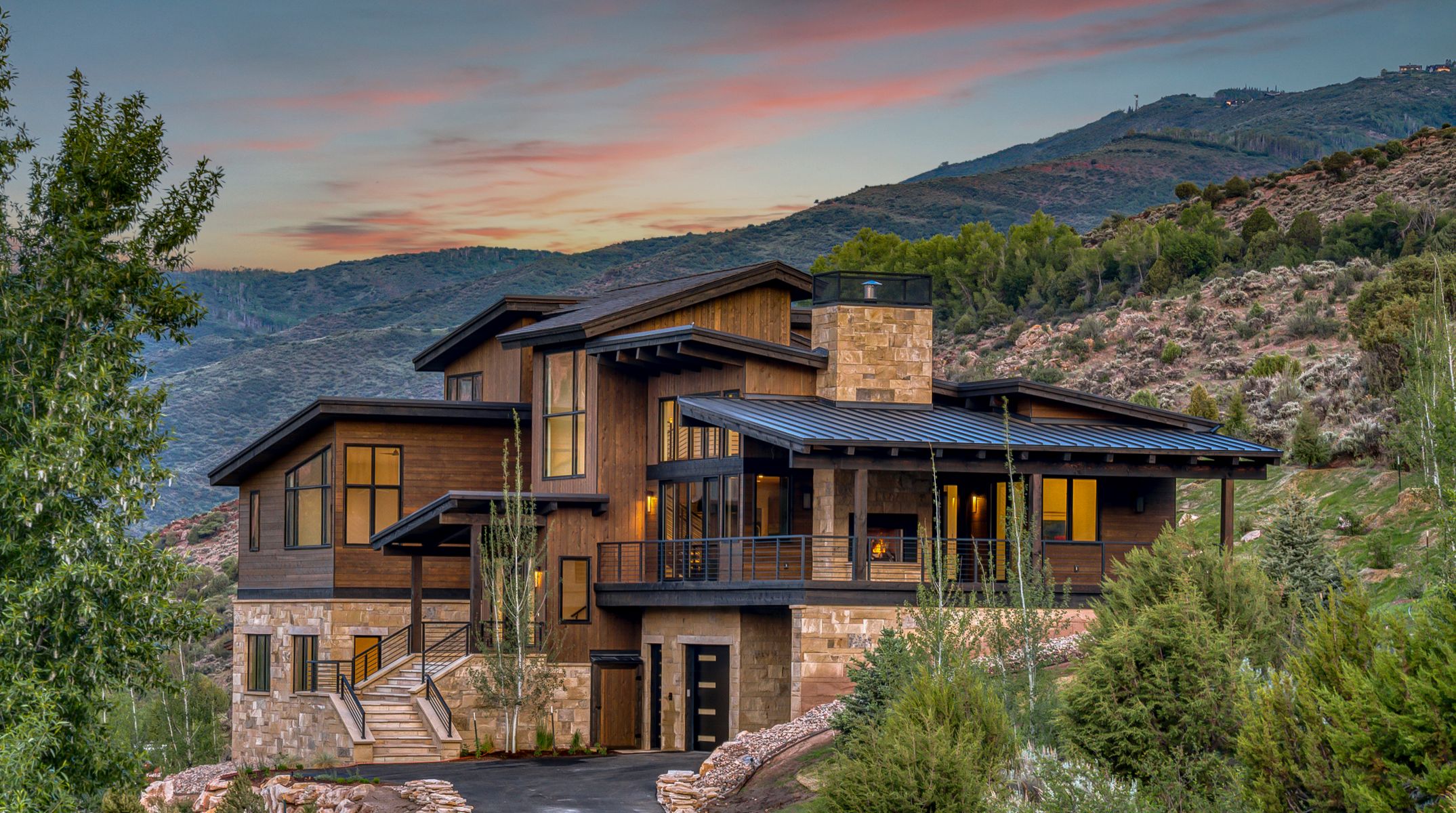 Rustic modern mountain home built by H&C Construction in Beaver Creek, Colorado, featuring natural wood siding, stone masonry, and a multi-level design with sunset views