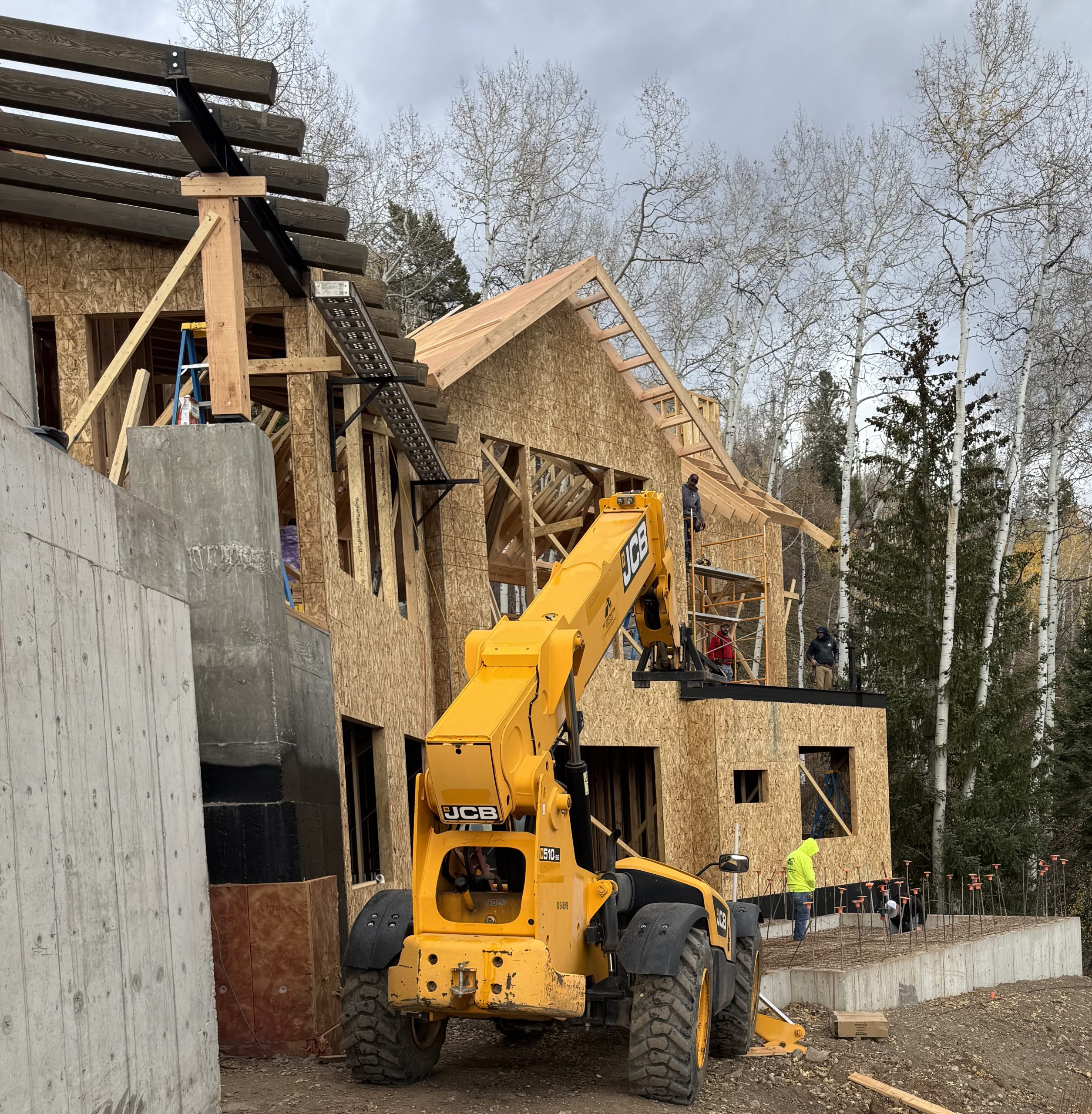Early stages of luxury home construction with concrete foundation walls and heavy equipment in Avon, Colorado